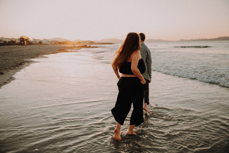 Romantisches Couple Shooting bei Sonnenuntergang – Paar spaziert barfuß am Wasser im Licht der untergehenden Sonne