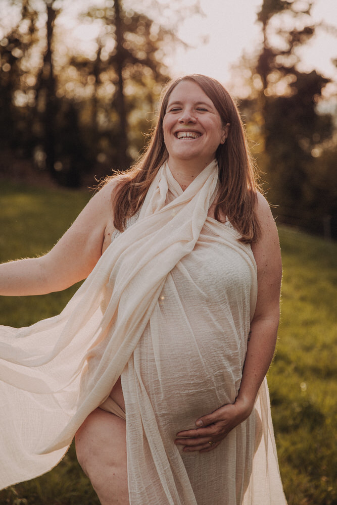 Babybauch Shooting im Gras bei Sonnenuntergang – natürliche Schwangerschaftsfotografie