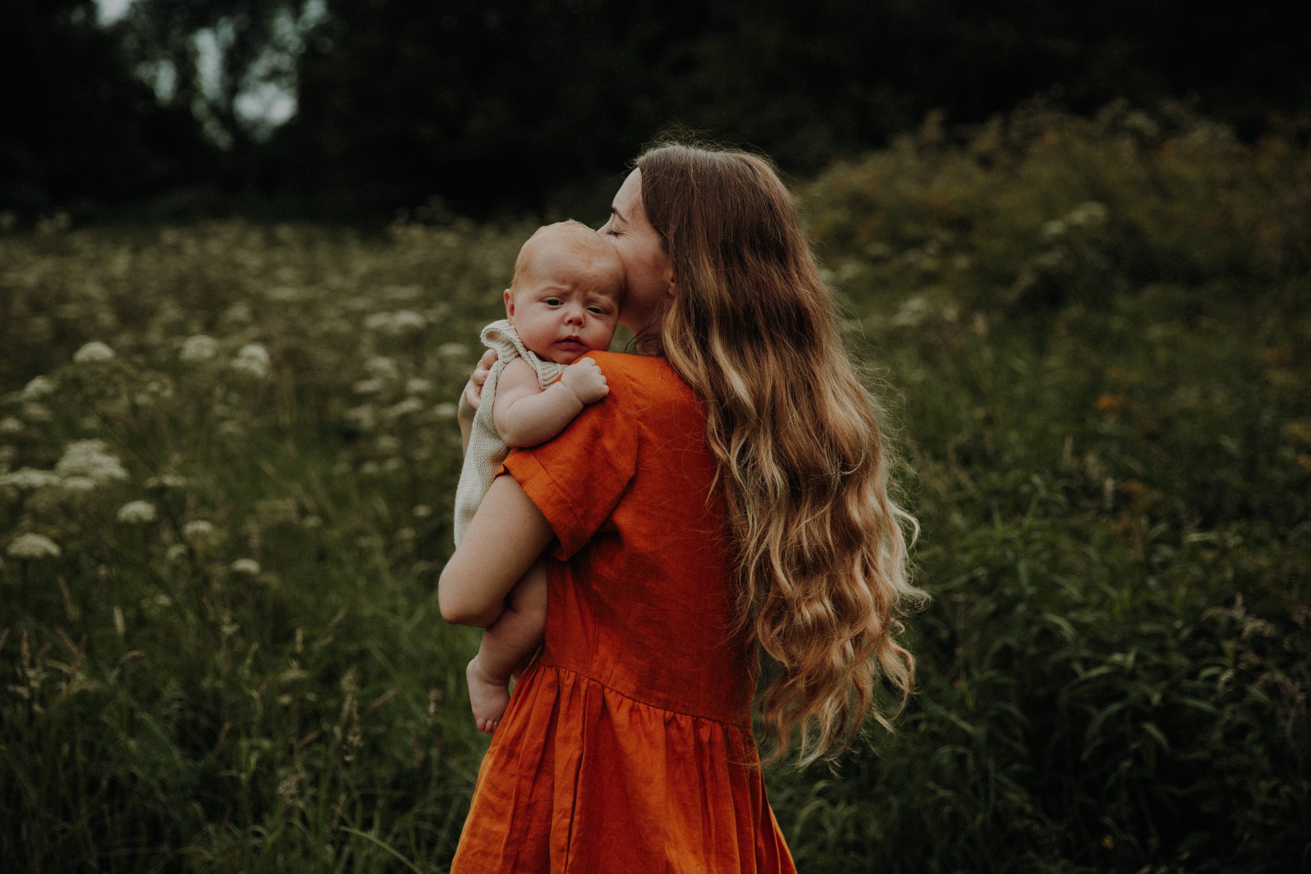 Mutter hält ihr Baby im Arm auf einer sommerlichen Wiese
