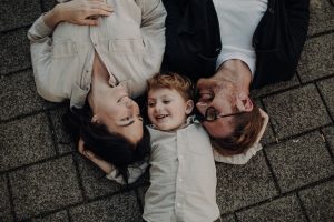 Familien Fotoshooting – Eltern und Kind liegen lachend nebeneinander