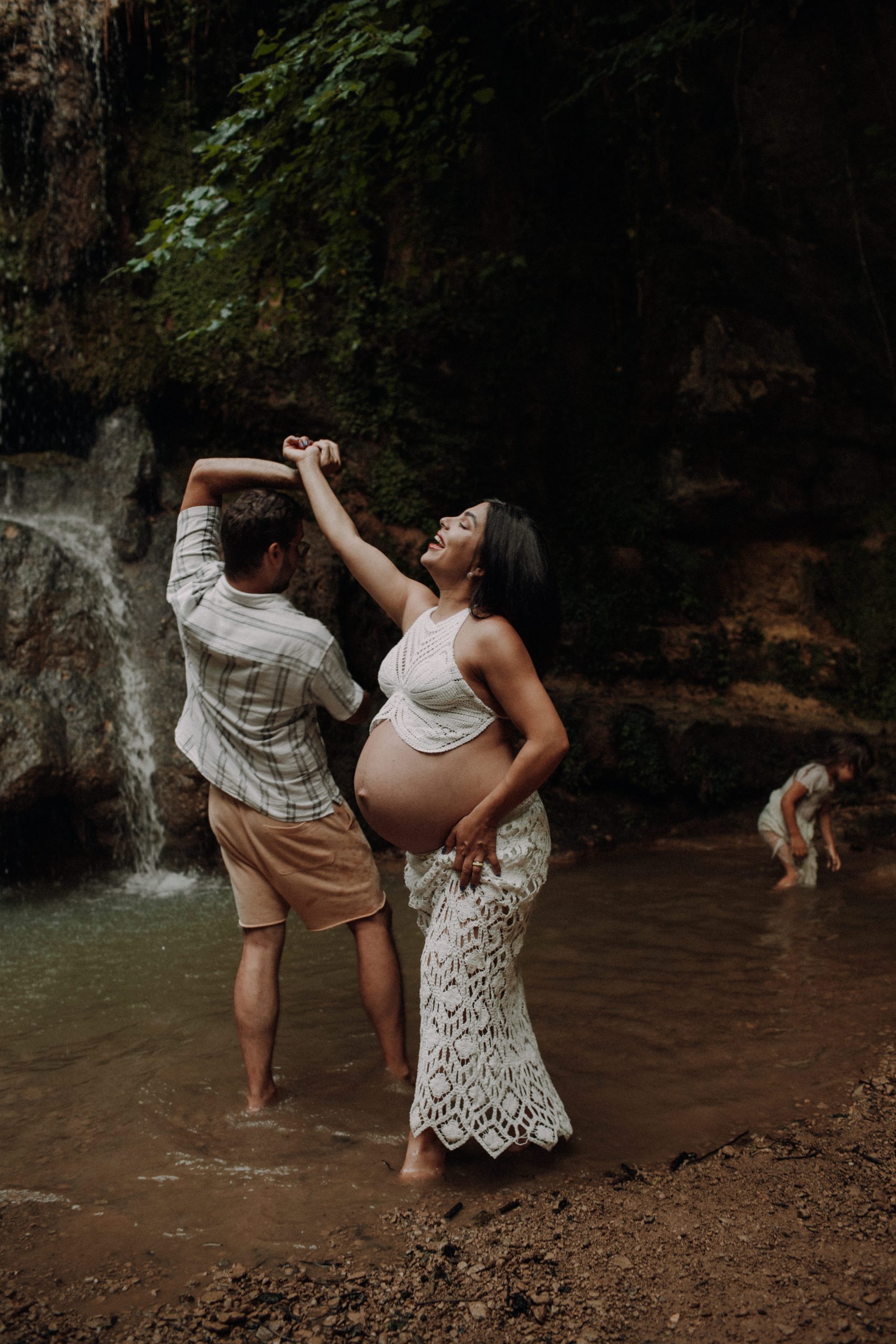 Ein schwangeres Paar tanzt im Wasser.