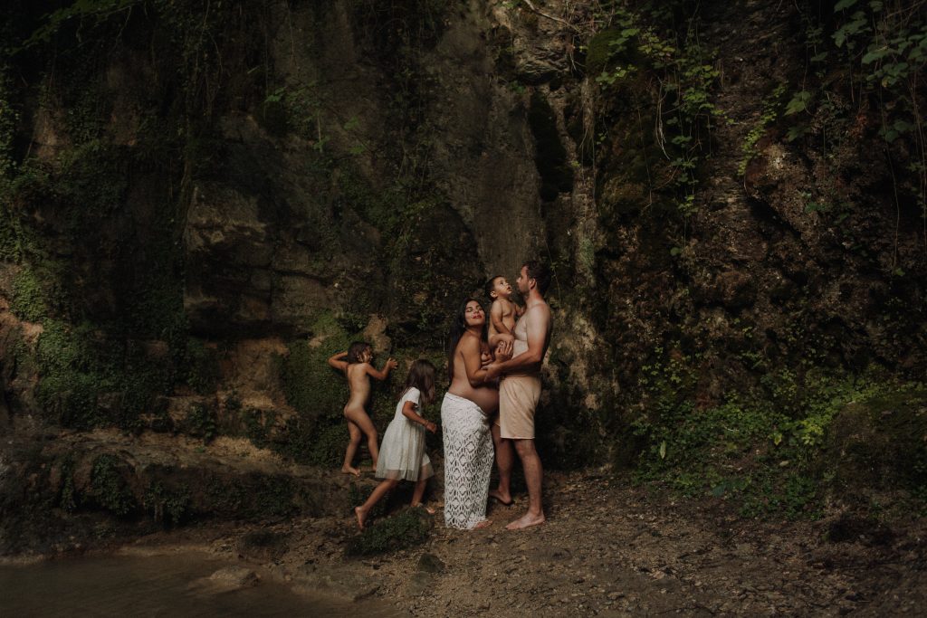 5-köpfige Familie bei Babybauchshooting vor einem Wasserfall. Kunstvolles Familienfoto
