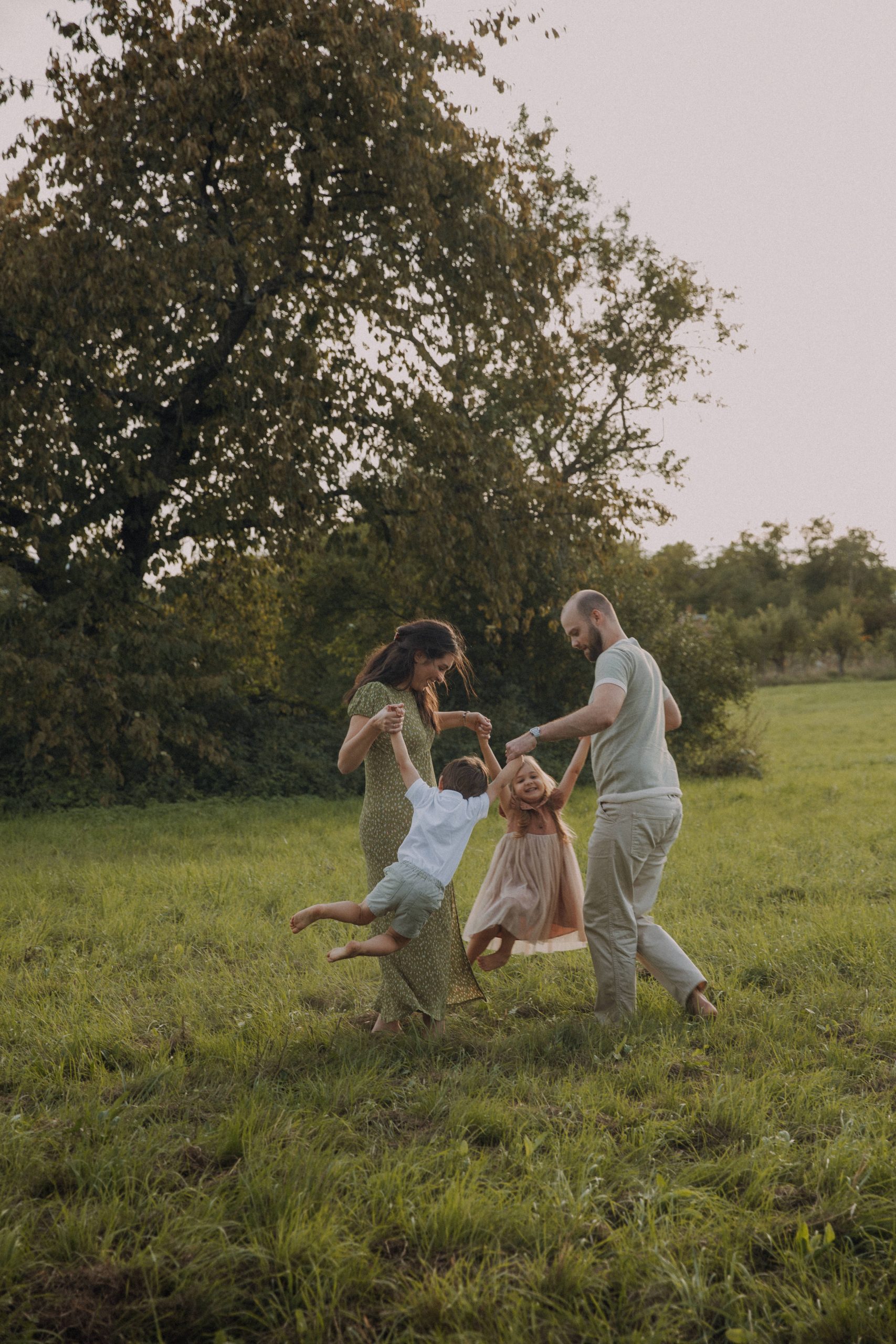 Familien Fotoshooting im Grünen – Eltern spielen mit ihren Kindern auf einer Wiese