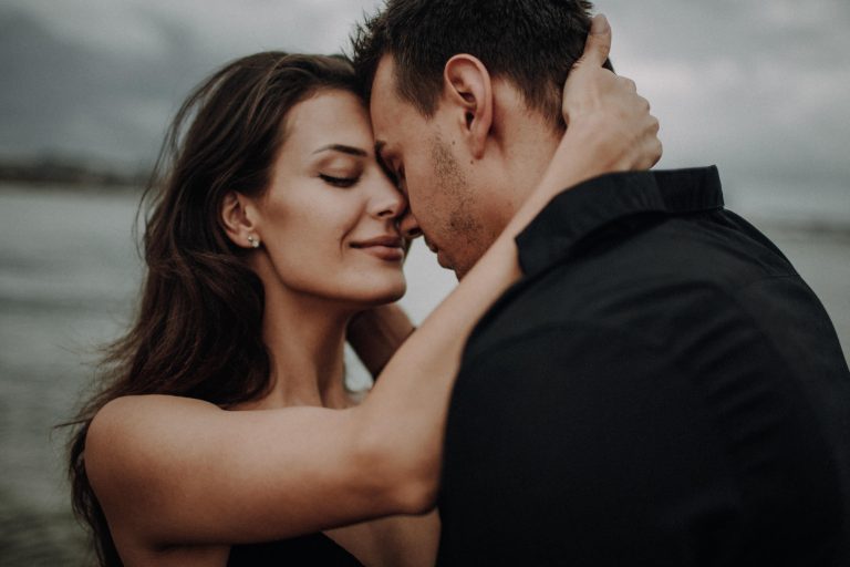 Emotionales Couple Shooting am See – verliebtes Paar in innigem Stirn-an-Stirn-Moment vor dramatischem Himmel