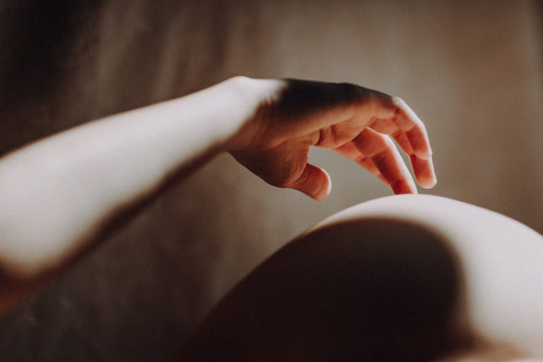 Elegantes Boudoir Shooting – künstlerische Detailaufnahme einer Hand in warmem Licht mit weichen Körperkurven