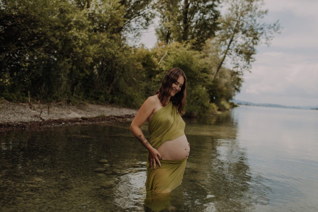 Schwangerschaftsfotoshooting, Frau in Wasser, Brüste mit grünem Tuch bedeckt