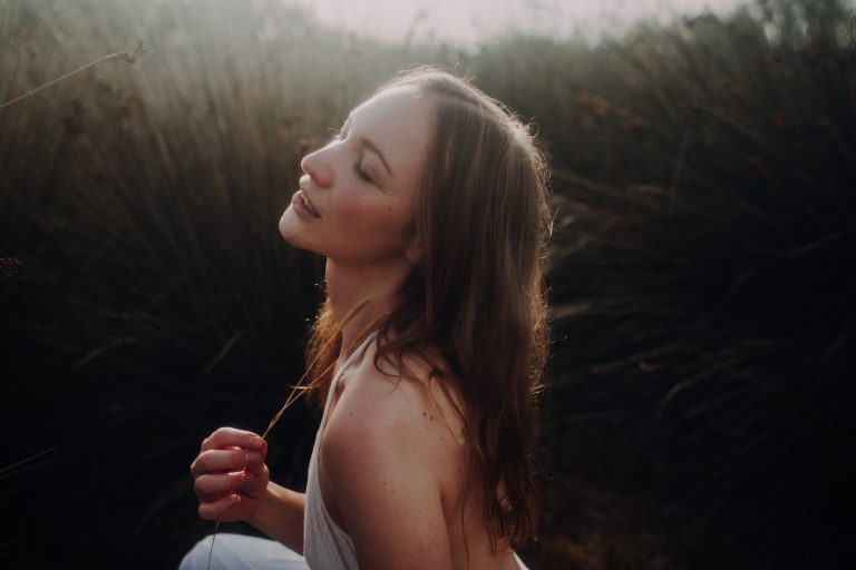 Fine Art Boudoir Outdoor– träumerische Frau mit geschlossenen Augen im warmen Gegenlicht zwischen Wildgräsern