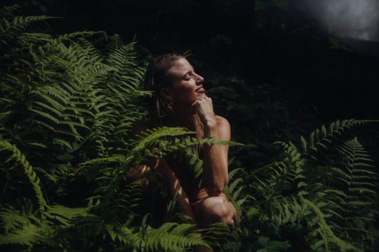 Naturverbundenes Fine Art Boudoir Shooting – Frau zwischen üppigen Farnen im dramatischen Waldlicht